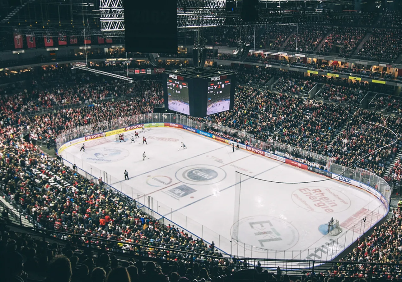 A wide view of an ice arena during a hockey game with a large crowd.