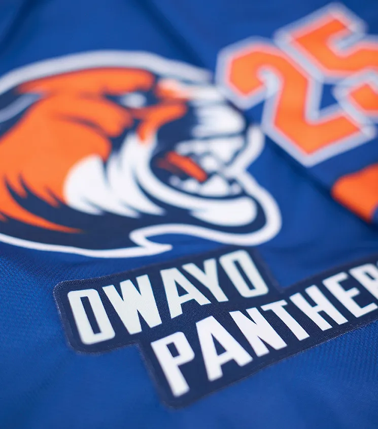 Close-up of a blue sports jersey featuring an orange panther logo and the text 'OWAYO PANTHERS' in white lettering on a dark patch.