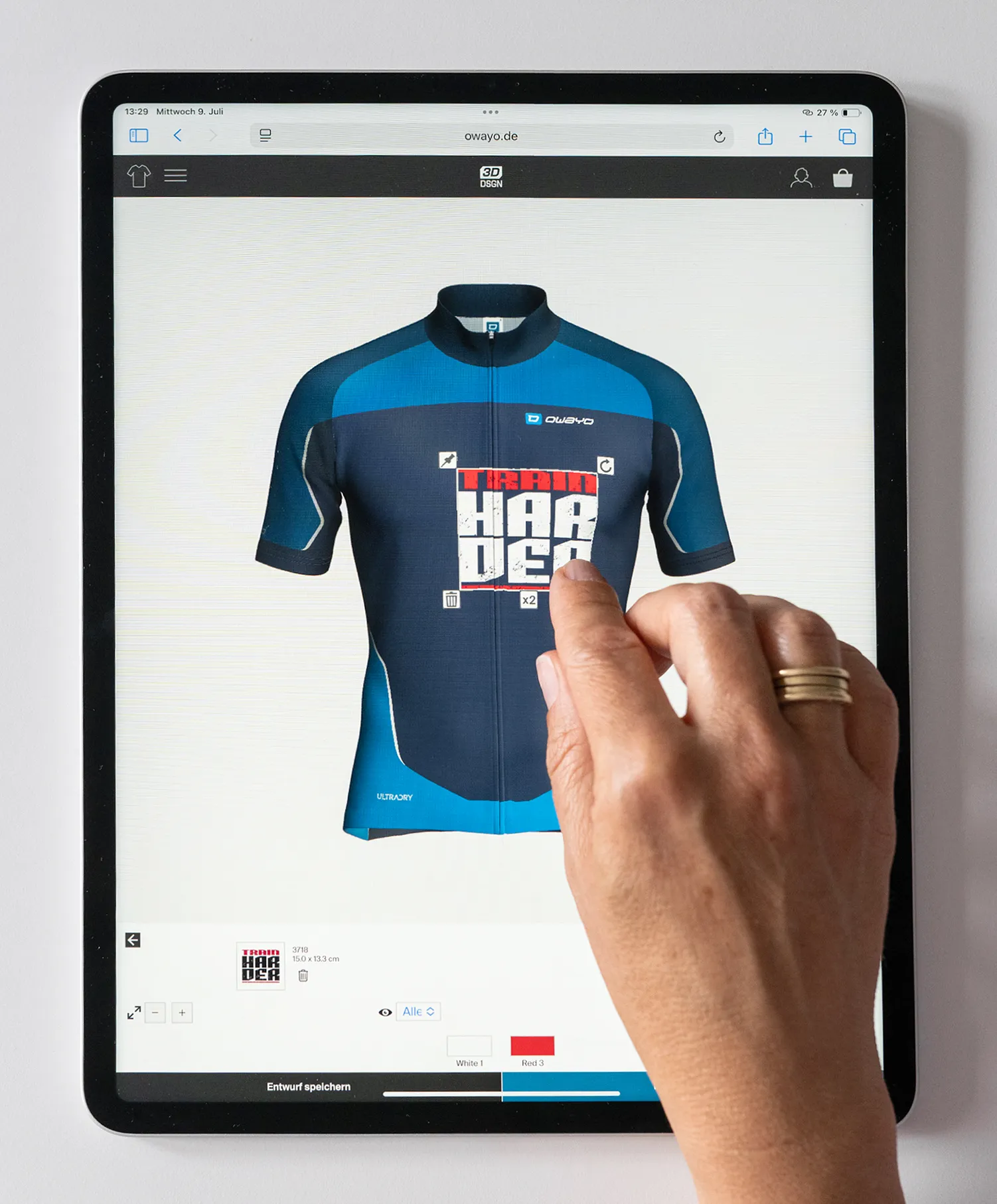 A hand interacts with a tablet displaying the owayo website, showing a custom-designed blue and dark blue cycling jersey with the text 'TRAIN HARDER'.
