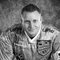 A man wearing a sporty, patterned jersey with various sponsor logos, including Red Bull and LaPati, and the text 'owayo' on the chest.